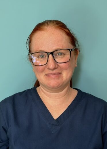 woman with glasses and ponytail in dark blue nurses uniform