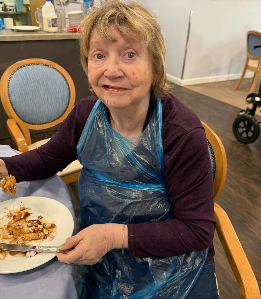 woman smiling while eating a chocolate covered pancake
