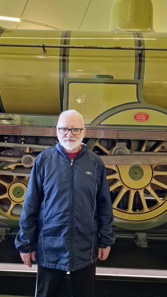 resident posing with train in museum