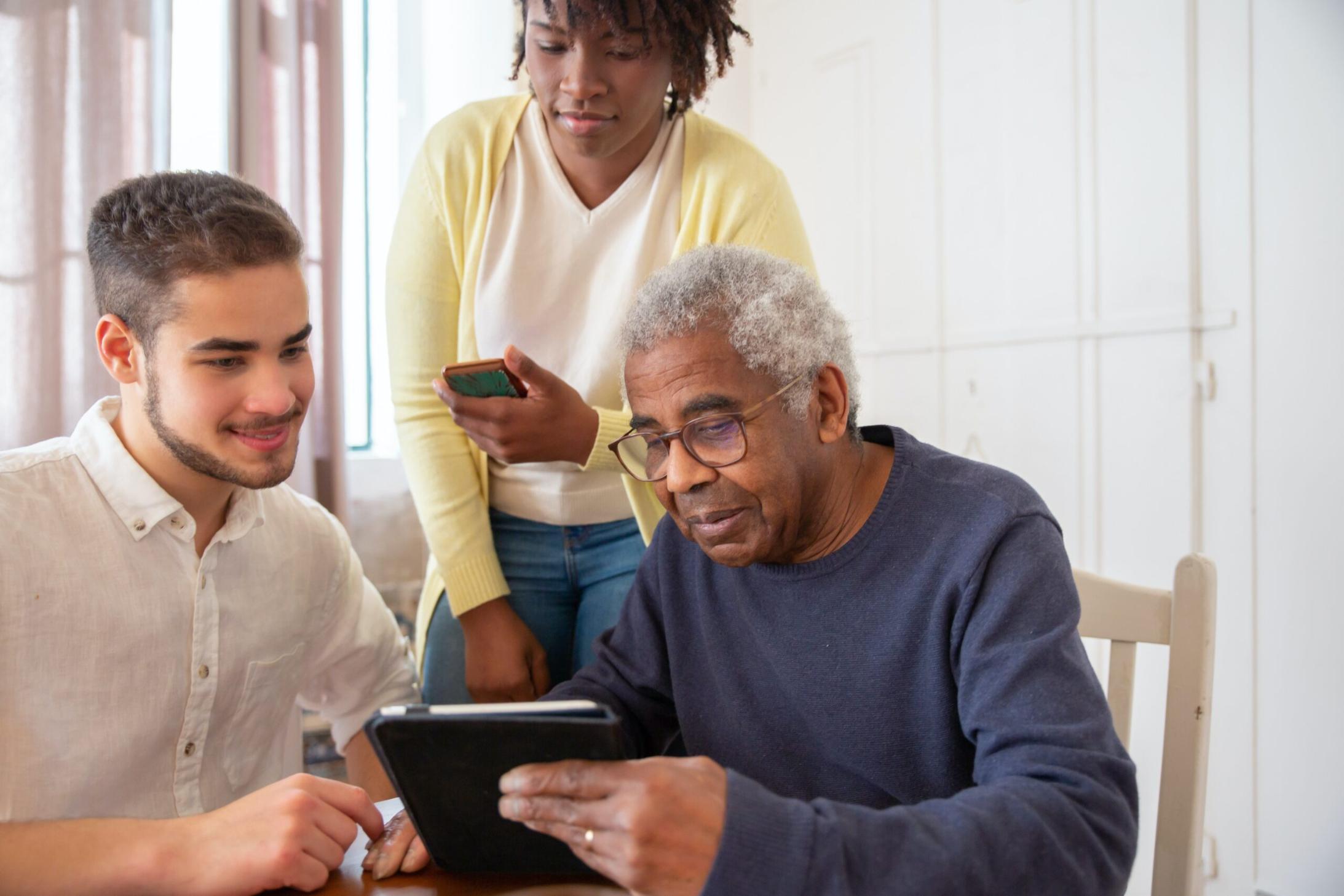 carer helping elderly couple use a tablet