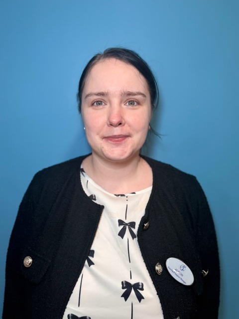 woman with brown hair tied back wearing a black cardigan