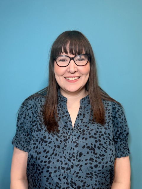 woman with dark hair and glasses smiling