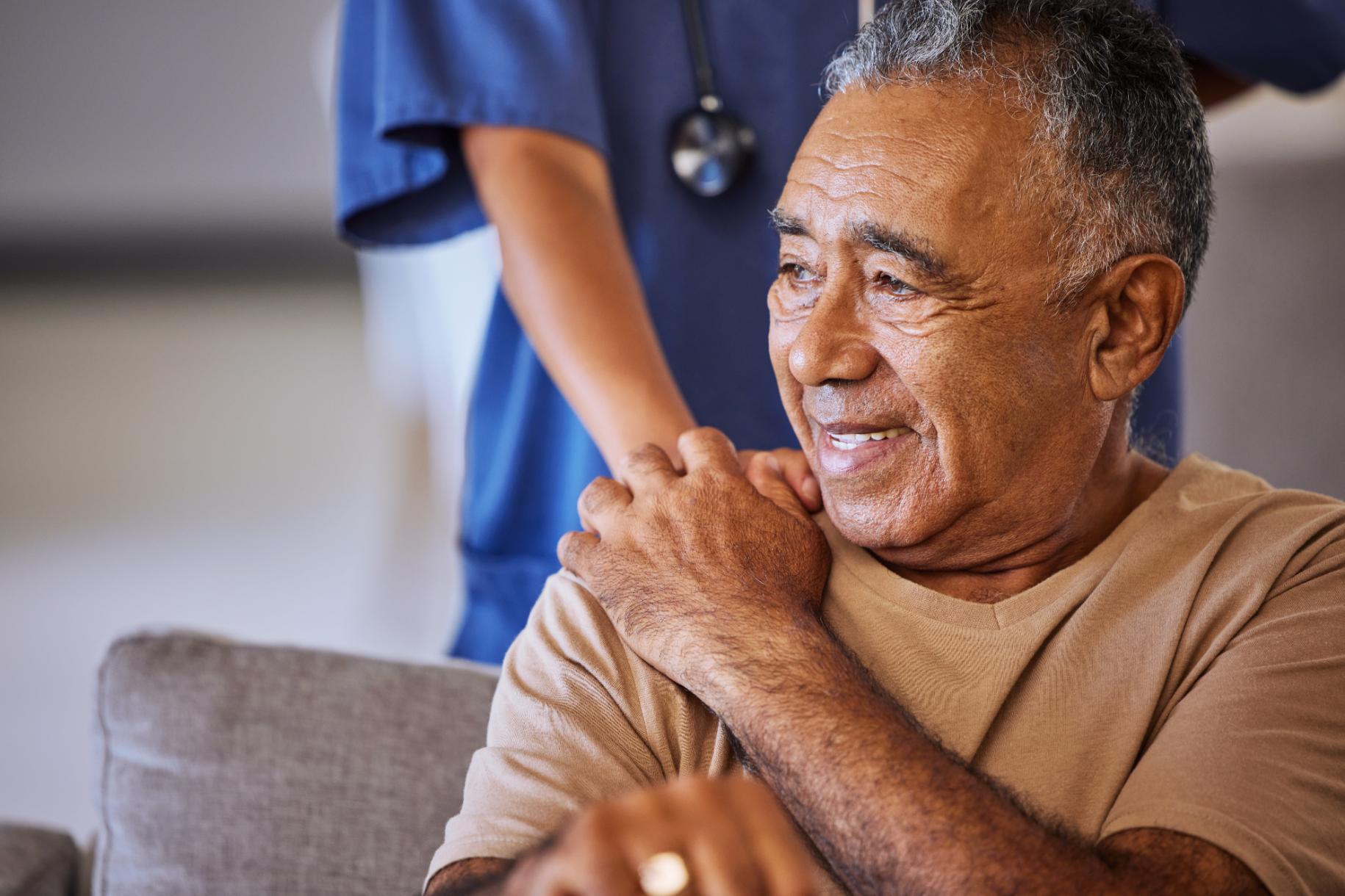nurse with hand on elderly care home resident's shoulder