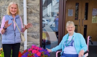 two residents next to some pink and purple flowers